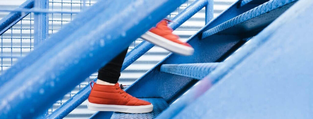 Person in red trainers climbing blue stairs.