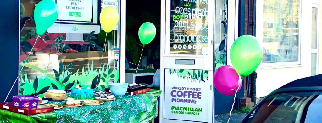Macmillan coffee morning event with balloons and treats.