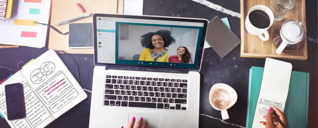 Video conference on laptop, workspace essentials visible.