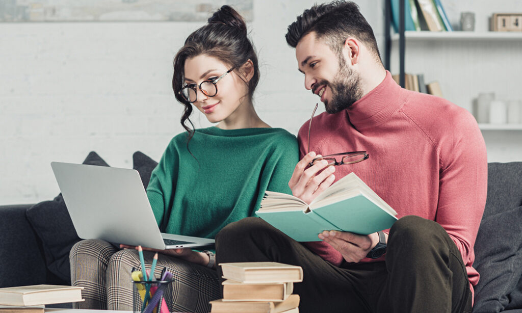 Two people studying with laptop and books.