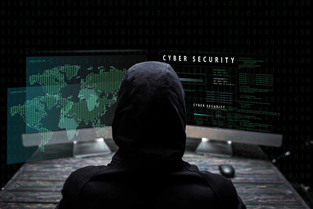 Hacker in front of cybersecurity screens.
