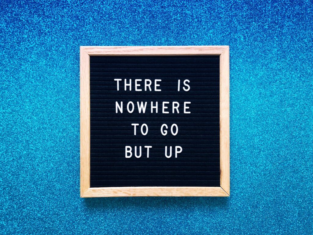 Motivational quote on board with blue glitter background.