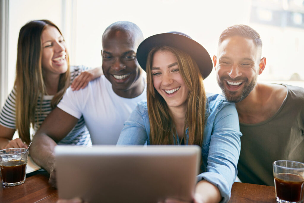 Group laughing together at a tablet in café