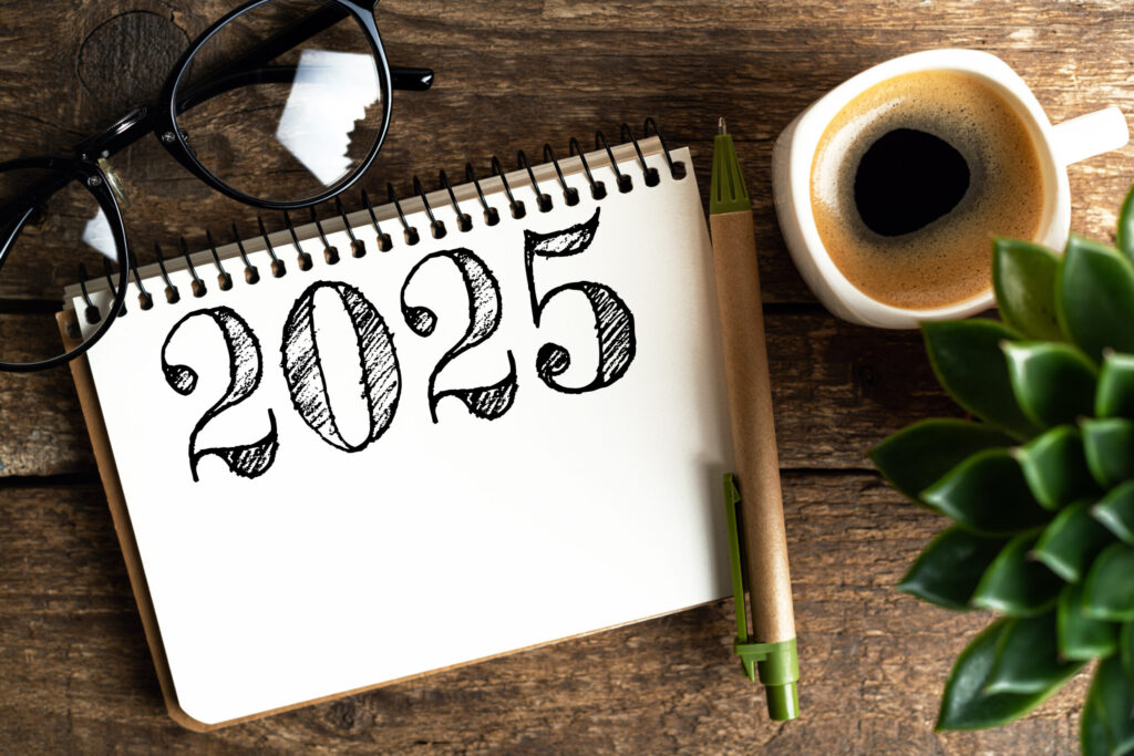 Notebook with '2025', glasses, coffee, and plant