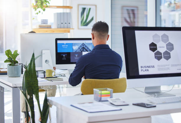 Man working at desk with computer screens.