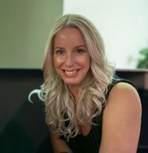 Smiling person with long blonde hair in office.