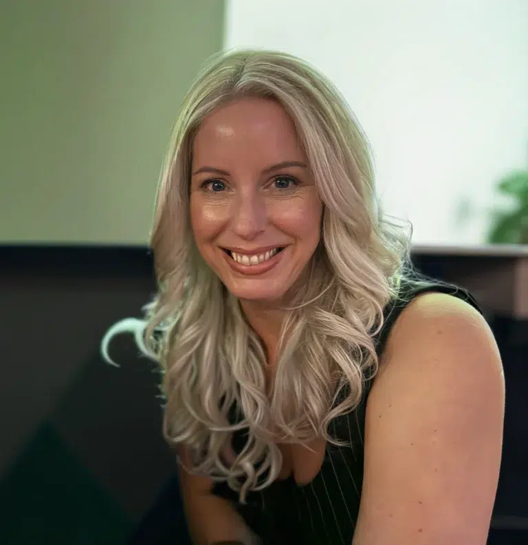 Smiling person with long blonde hair in office.