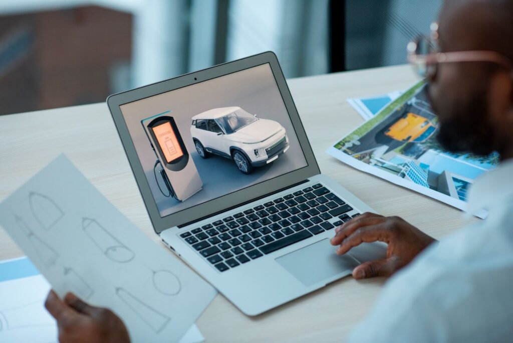 Designer reviewing electric car charging model on laptop.